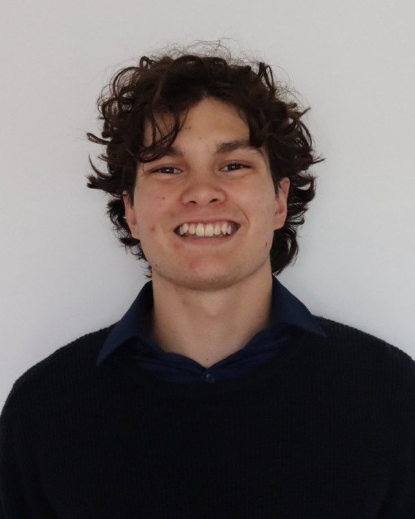Eric Webb, smiling, in a dark jumper and collared shirt